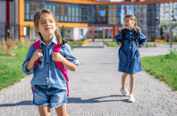 pupils-primary-school-girls-with-backpacks-near-building-outdoors-beginning-lessons-first-day-fall